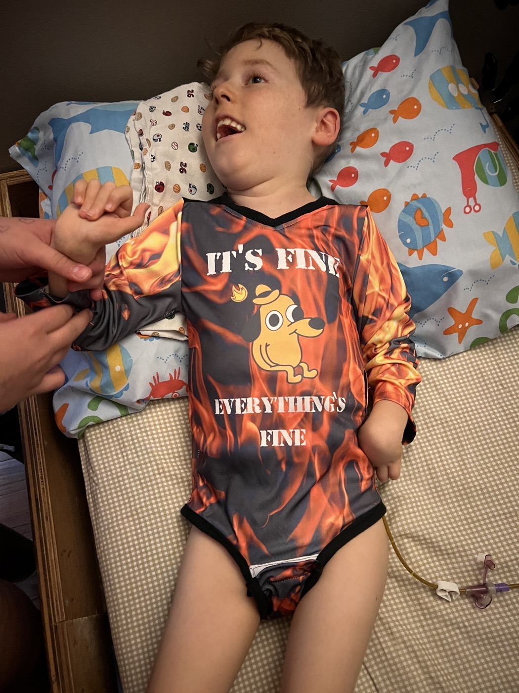 Jackson smiling in bed wearing an “It’s Fine” onesie