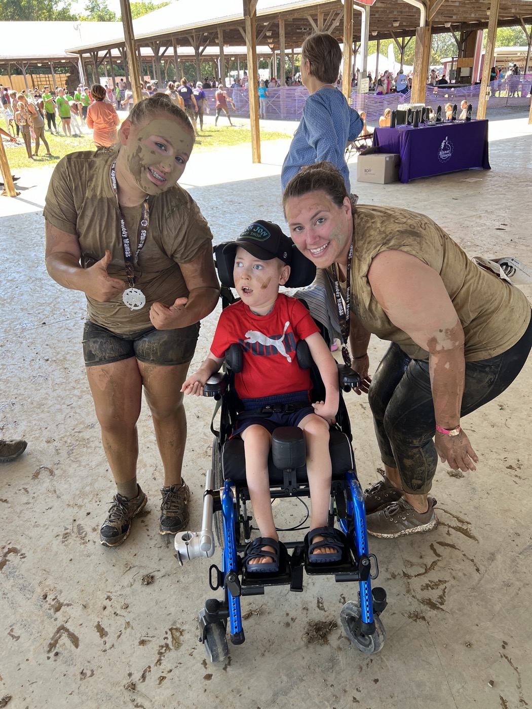 Ava and Heather muddy after a Muddy Mamas race, with Jackson in his wheelchair